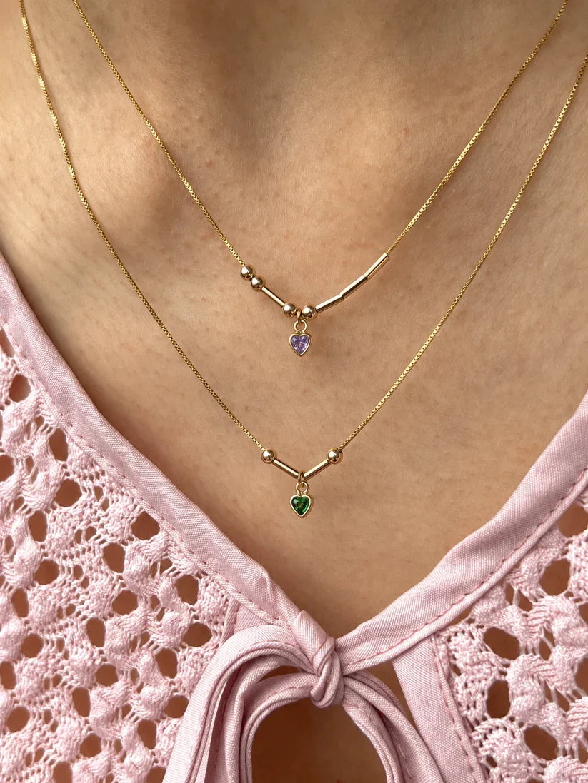 Custom two-initial Morse code necklaces finished in 22K gold, featuring personalized initials separated by tiny purple and green gemstone hearts[cite: 8].