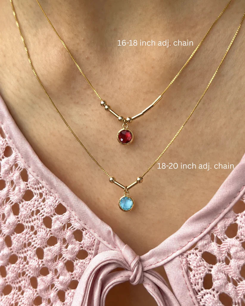 Two layered custom Morse code initial necklaces in 22K gold featuring vibrant red and blue 6mm birthstones, showcasing the adjustable chain lengths[cite: 9].