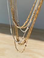 Layered collection of MCJ personalized unisex Morse code necklaces showcasing the 22K gold and rhodium silver finishes[cite: 14].