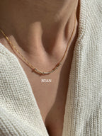 Unisex 22K gold plated custom Morse code necklace by MCJ spelling Ryan, showing minimal 4mm geometric beads[cite: 11].