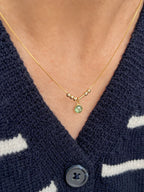 A minimalist 22K gold Morse code necklace featuring couple's initials and a bright green bezel-set anniversary birthstone charm[cite: 11].