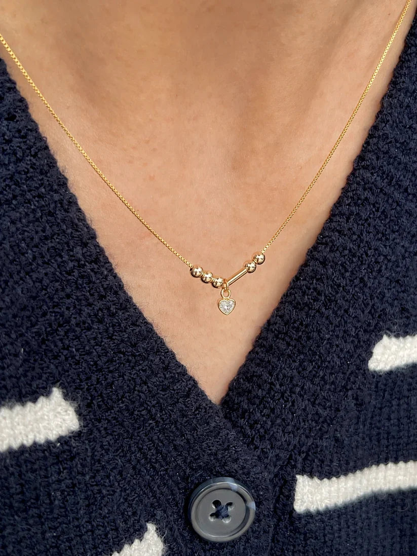 Close-up of a personalized couple's Morse code initial necklace in premium 22K gold plating, centered with a delicate clear heart stone pendant[cite: 9].